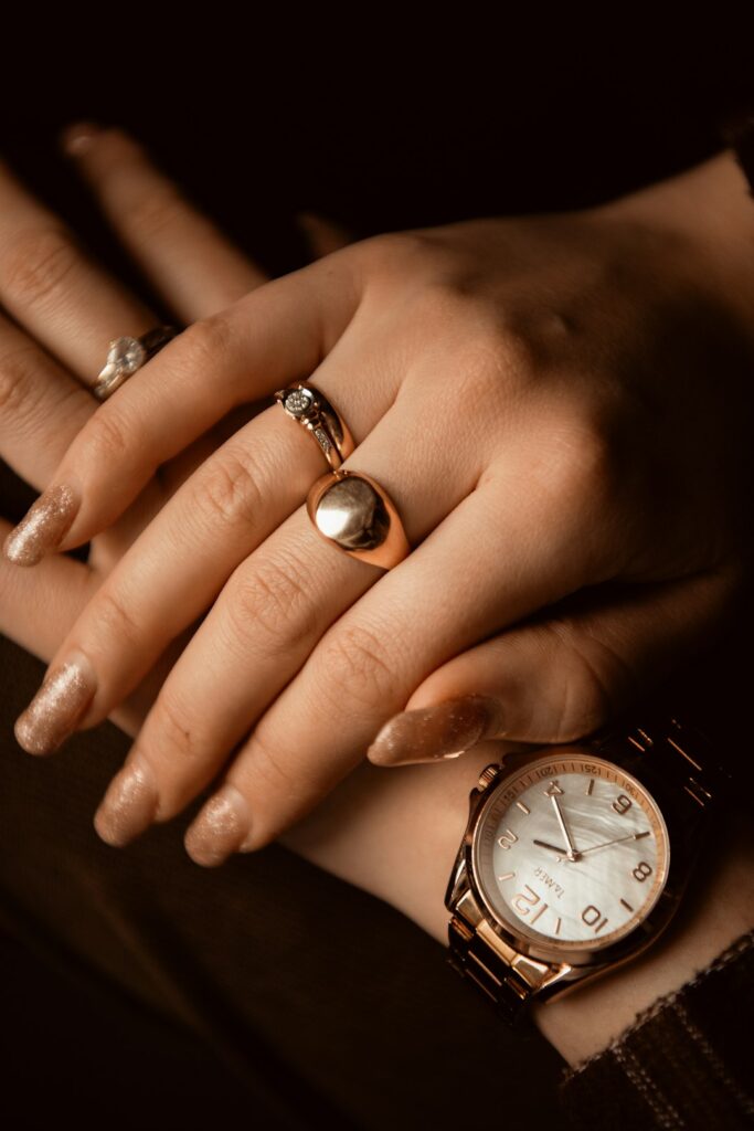 Person carefully removing a silver ring from a slightly swollen finger using soap and water at a bathroom sink.