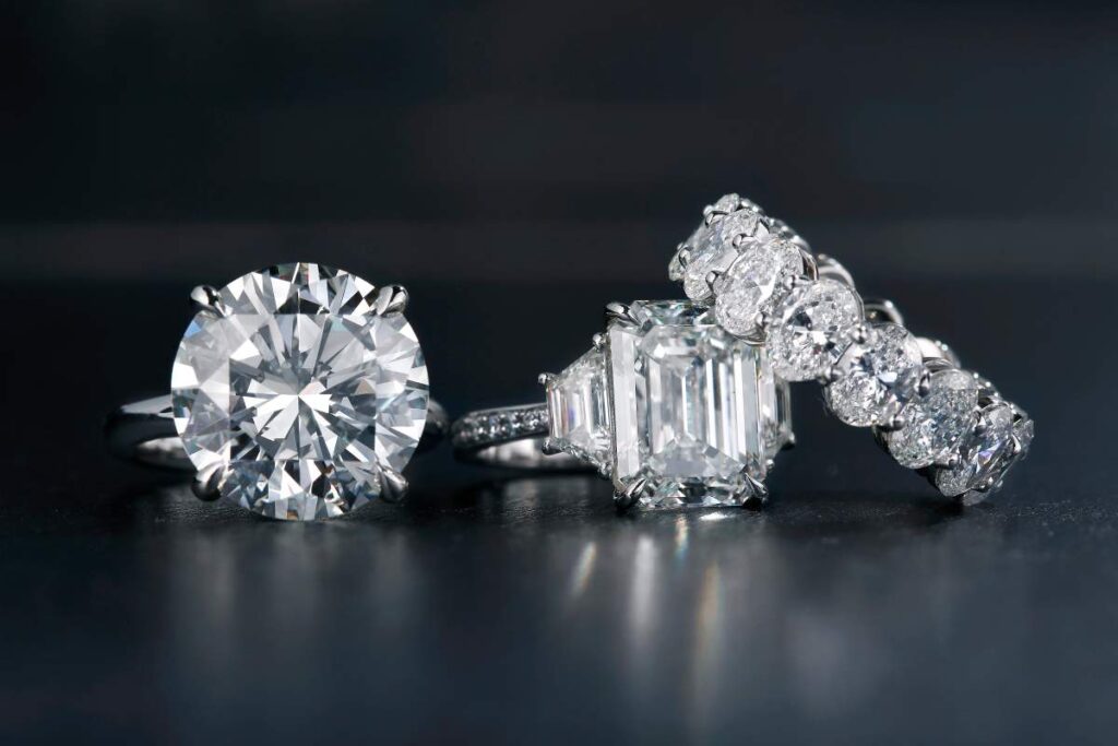A close-up of several fine jewelry pieces featuring heart, infinity, cross, and tree of life symbols displayed on a neutral background.